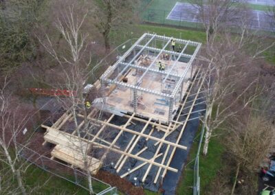 steel and wood frame of new theater building surrounded by trees with no leaves